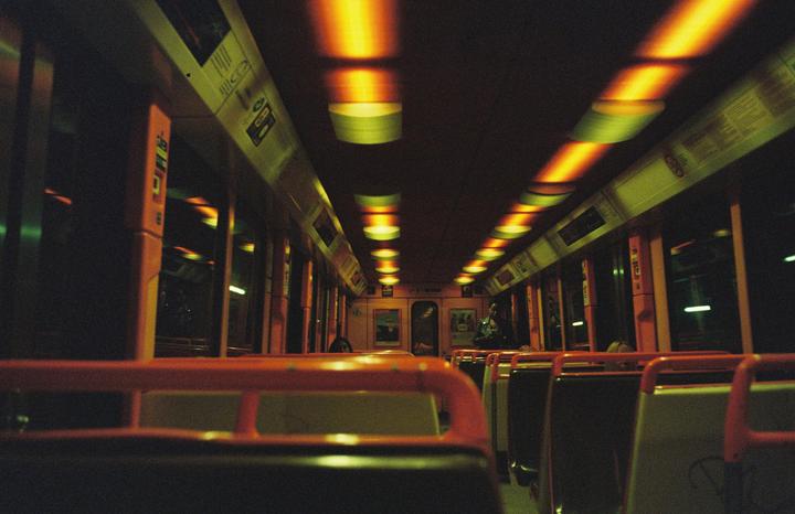 The interior of a subway car is illuminated by warm overhead lights.