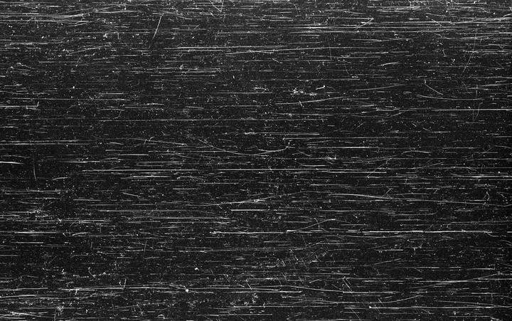 A black and white image shows numerous horizontal scratches and dust particles.