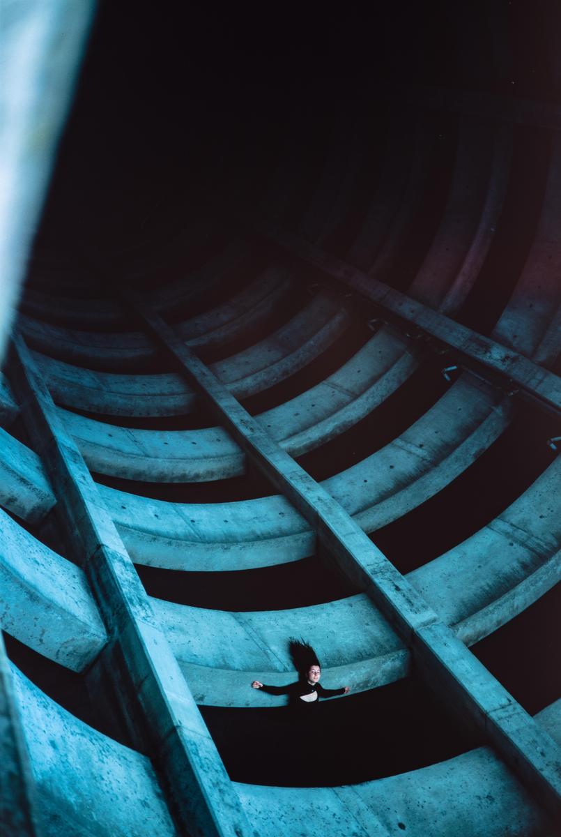 A woman lies on a concrete structure with her arms outstretched and hair fanned out.