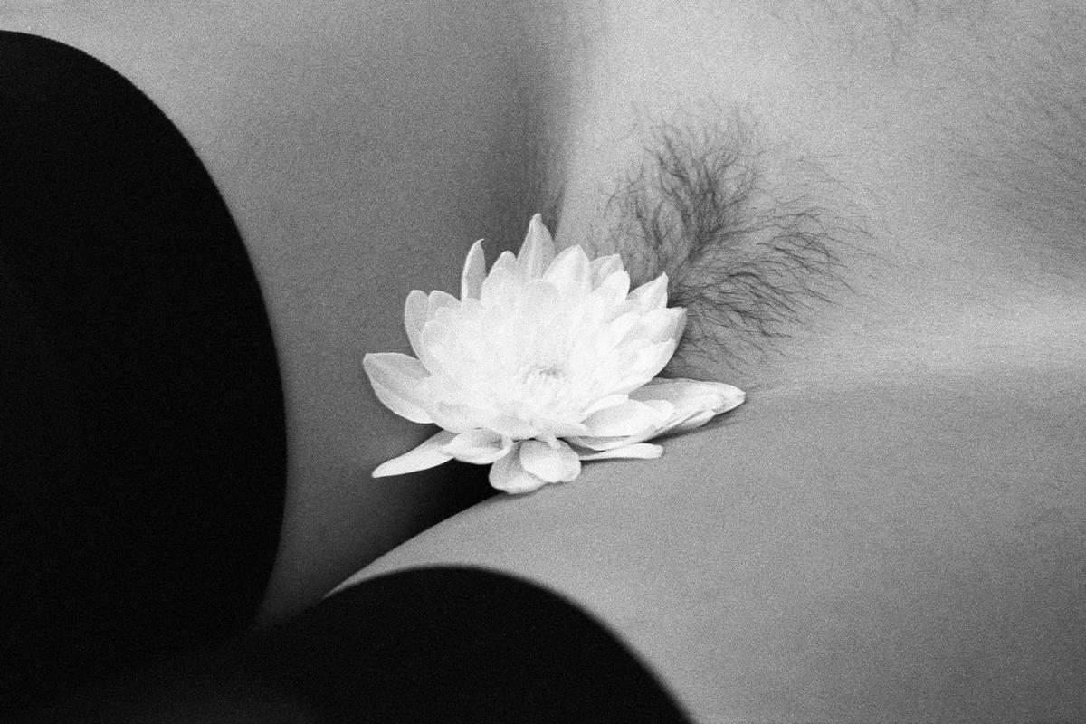 A white flower rests on a person's body, with dark hair visible behind it.