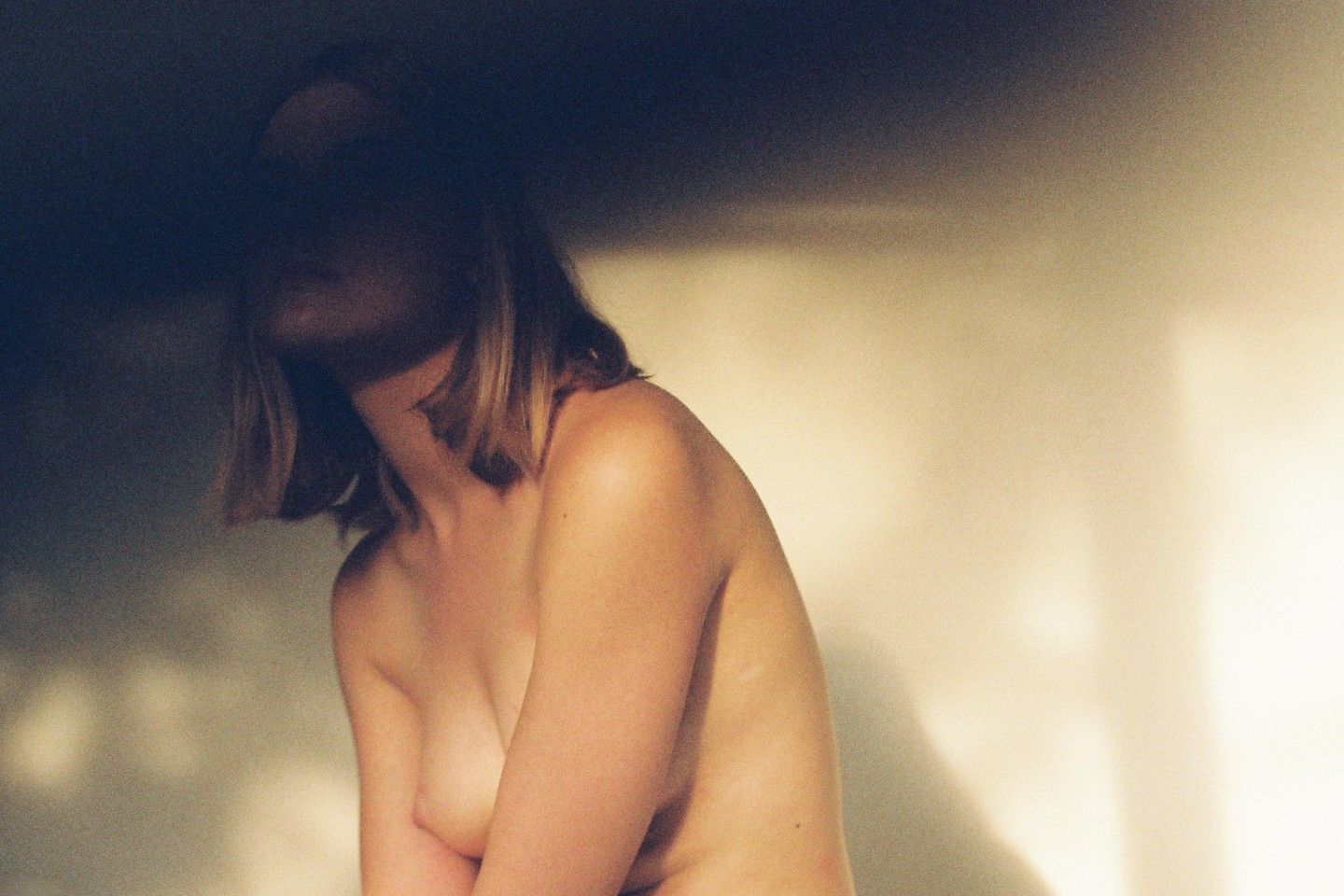 A woman with her face in shadow is illuminated by a warm light from the side.