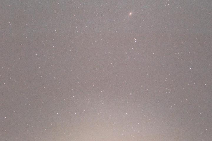 The Andromeda galaxy is visible among many stars in the night sky.