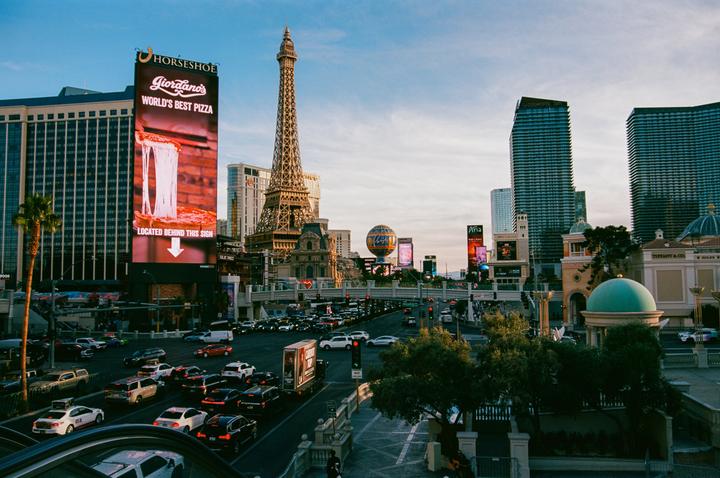 A busy street in Las Vegas is filled with cars and tall buildings, including a replica of the Eiffel Tower.
