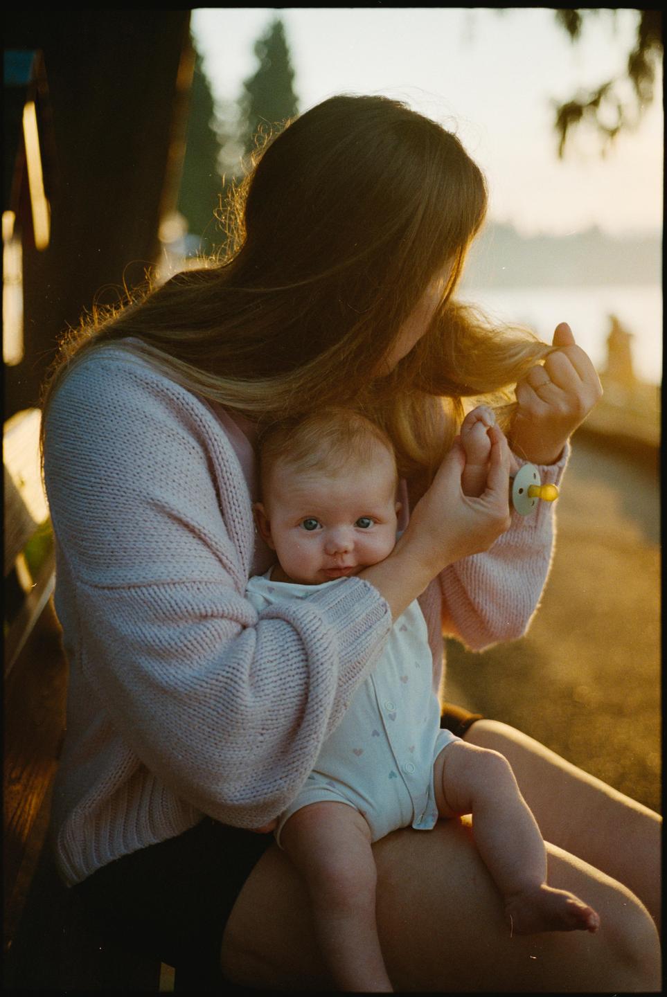 A woman holds a baby on her lap, with the baby looking directly at the viewer.