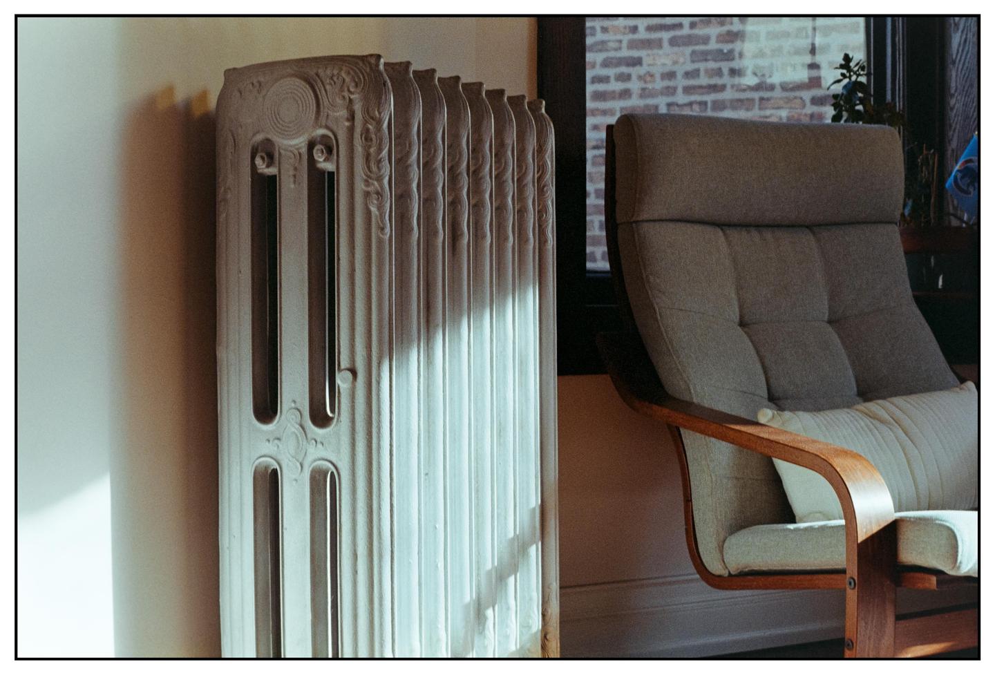 Sunlight illuminates a radiator and a chair in a room.