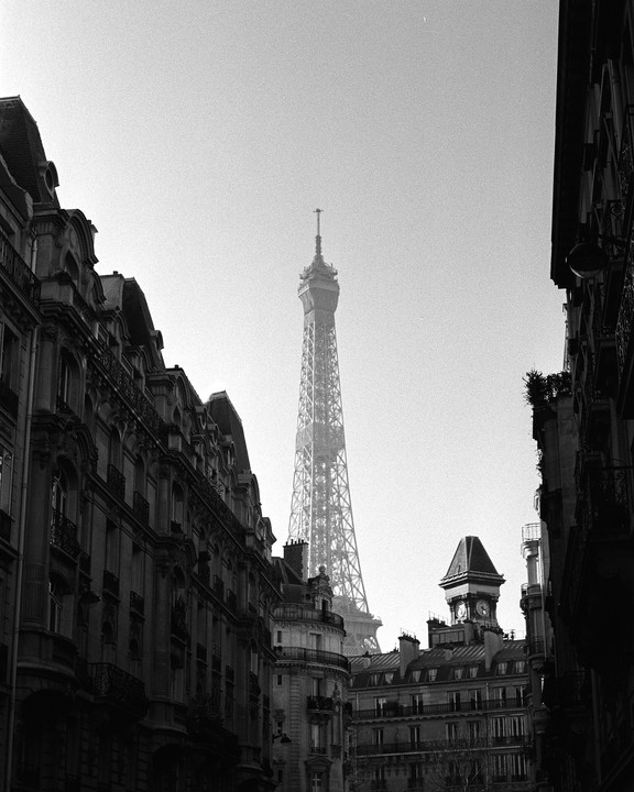 The Eiffel Tower rises above buildings in a city.