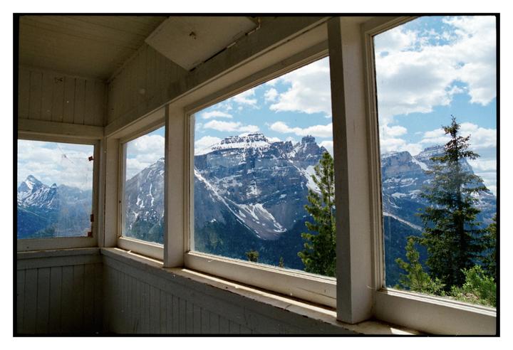 A snowy mountain range is visible through the windows of a wooden building.