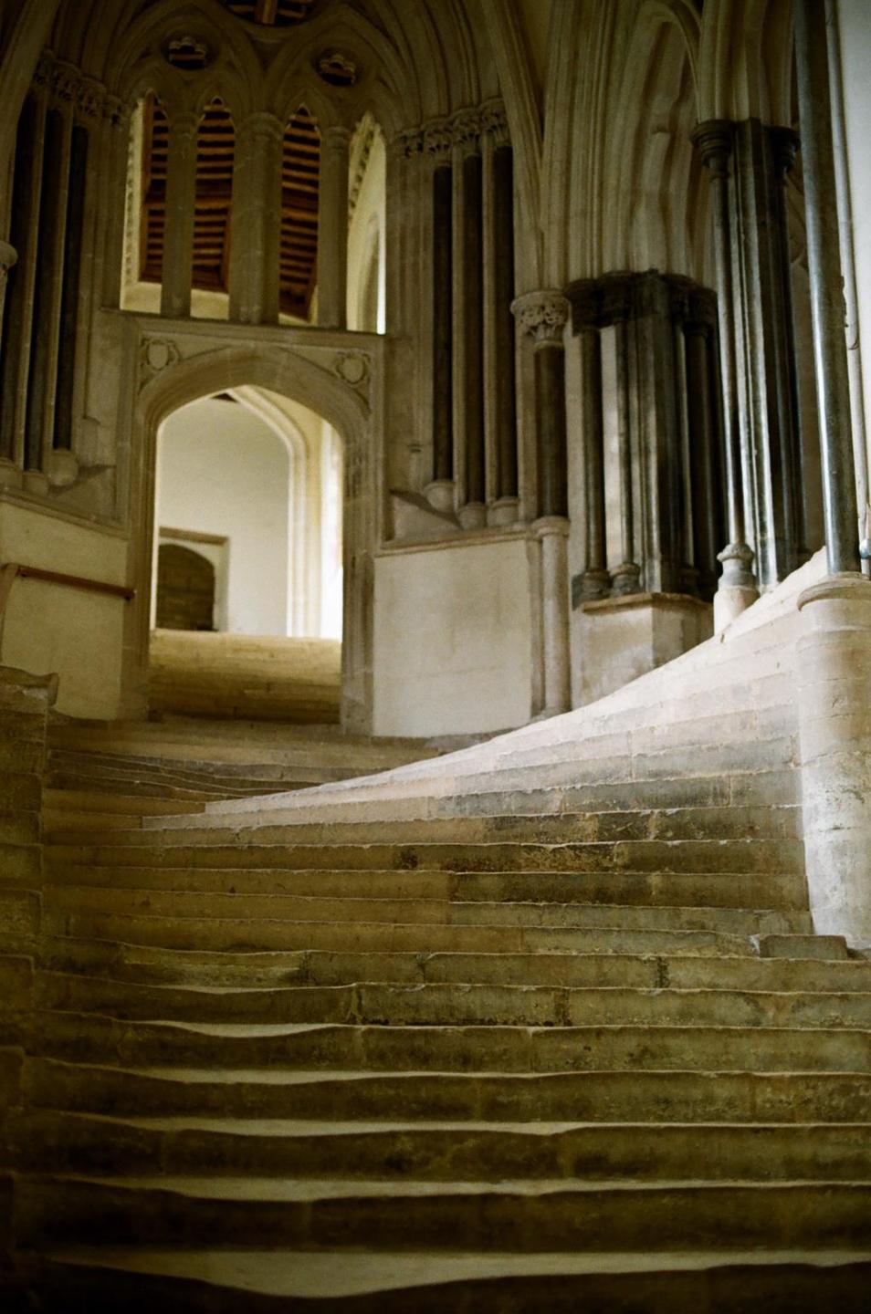 A stone staircase curves upwards towards an arched doorway in an ancient building.