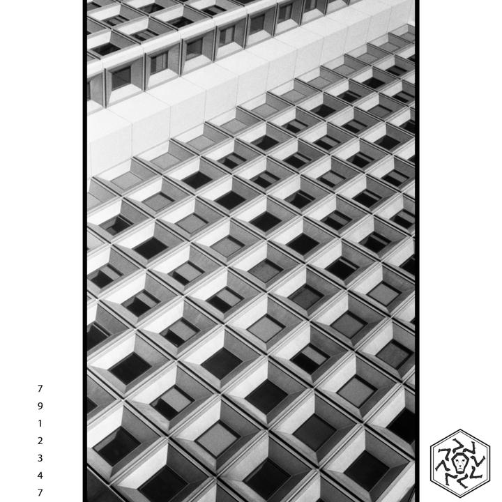 A building facade features a repeating pattern of square windows with deep recesses.