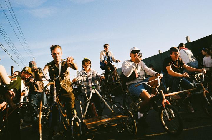 A group of people are riding bicycles on a street under a clear sky.