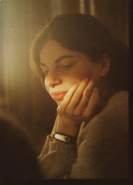 A woman with her hand on her chin looks down and to the side.