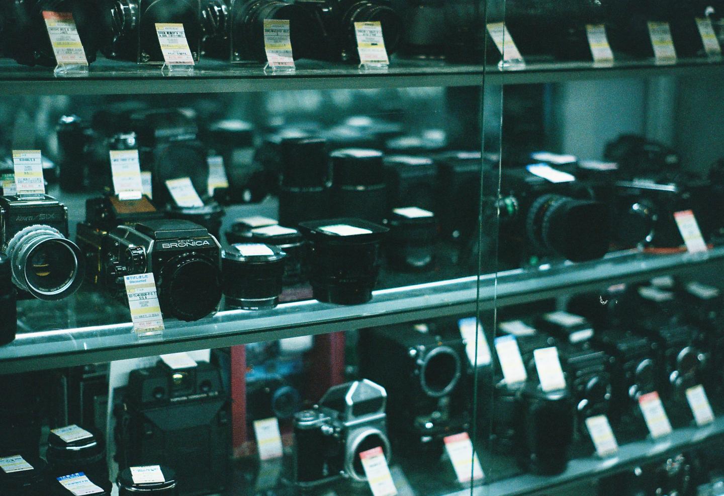 A display case filled with cameras and lenses is visible in a store.