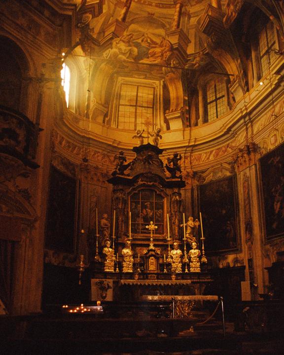 Sunlight streams through a high window onto the ornate altar of a church.