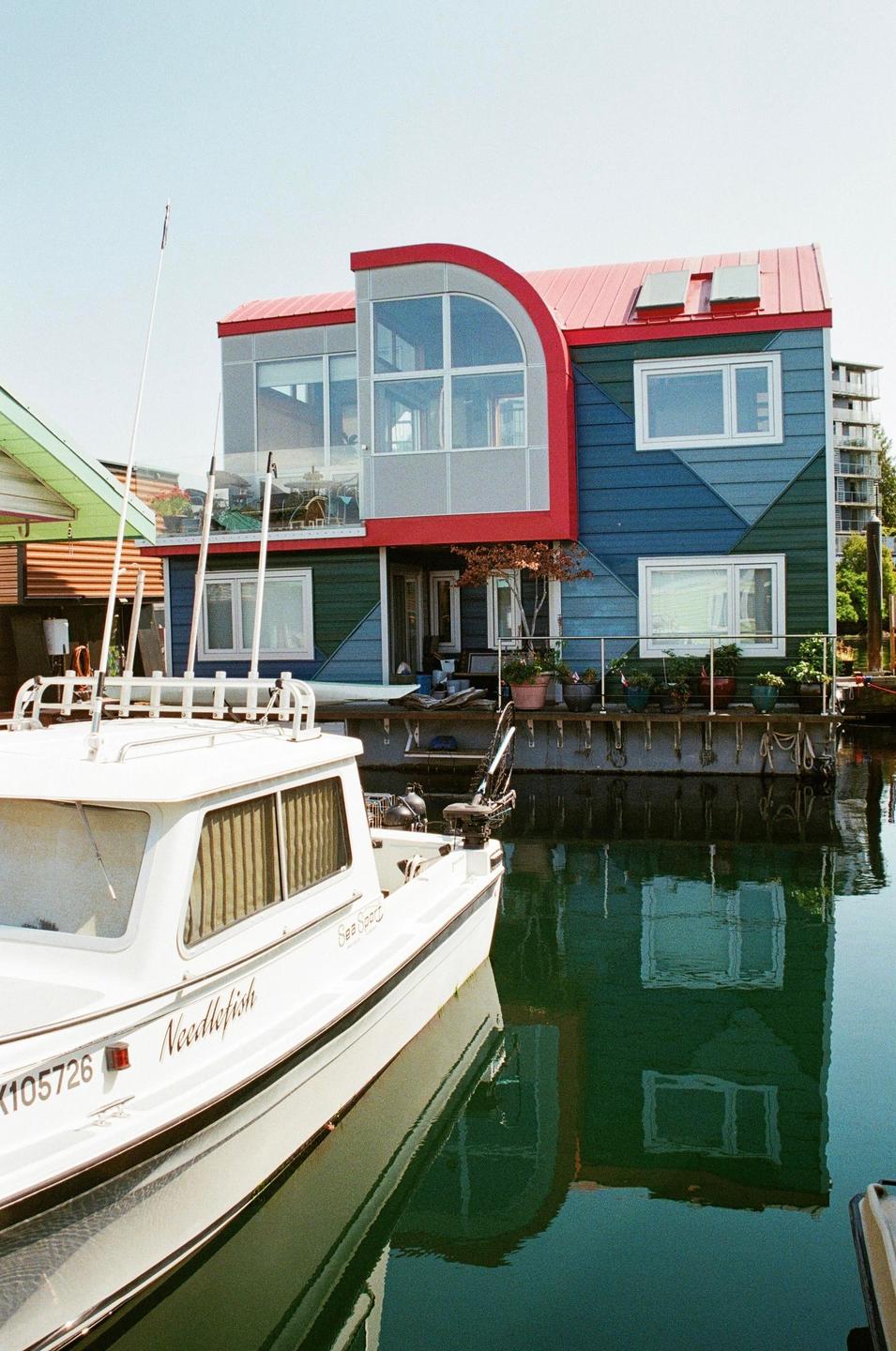 A white boat is docked in front of a colorful house on the water.