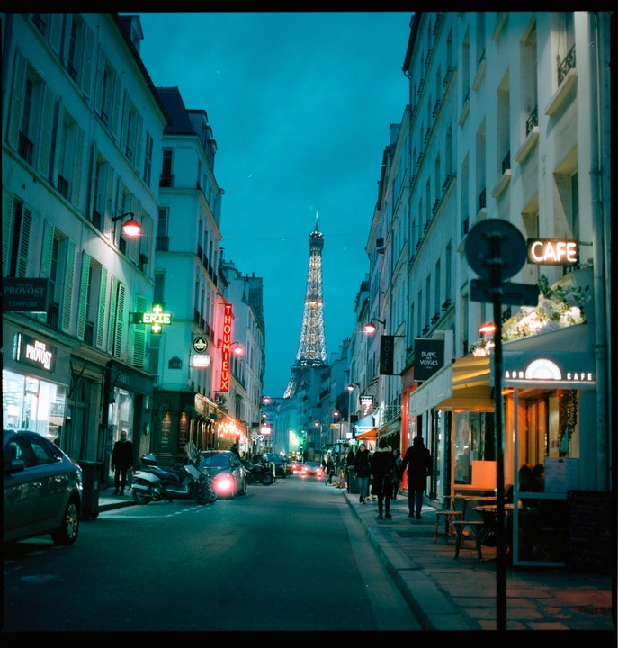 A street in Paris at dusk with the Eiffel Tower visible in the distance.