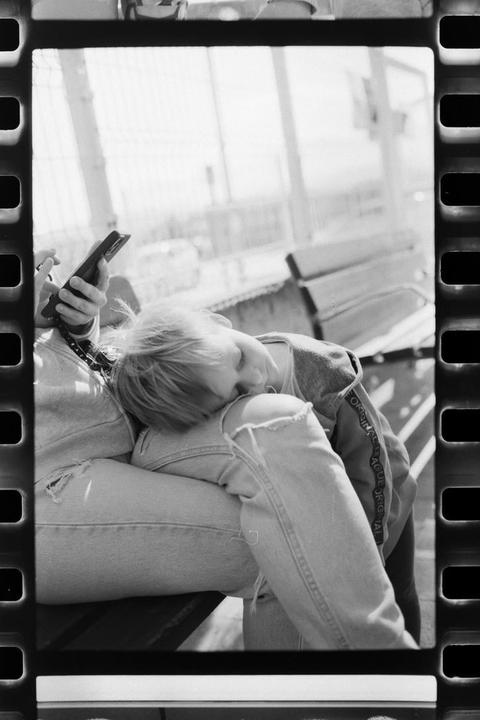 A child sleeps on a woman's lap while she holds a phone.