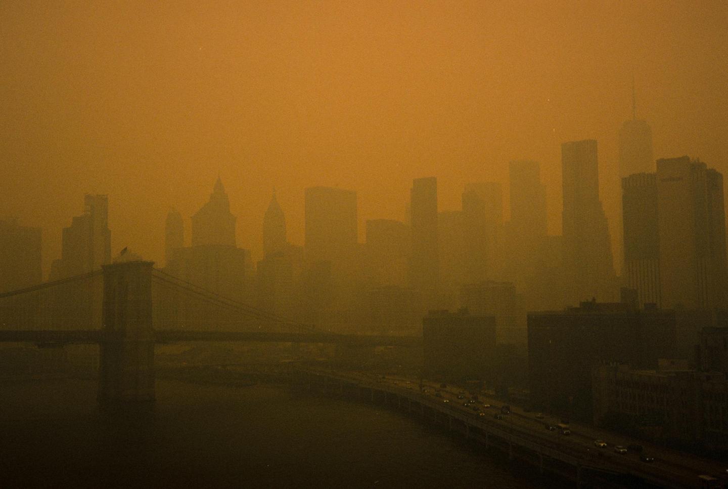 A hazy, orange-tinted skyline of a city with a bridge and a highway over water is visible.