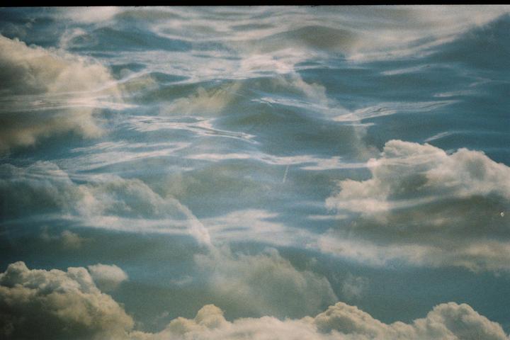A double exposure shows clouds in the sky and waves on the ocean.