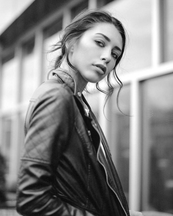 A woman wearing a leather jacket looks over her shoulder at the viewer.
