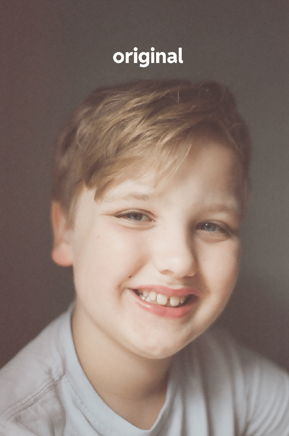 A young boy with blond hair and blue eyes smiles at the viewer.