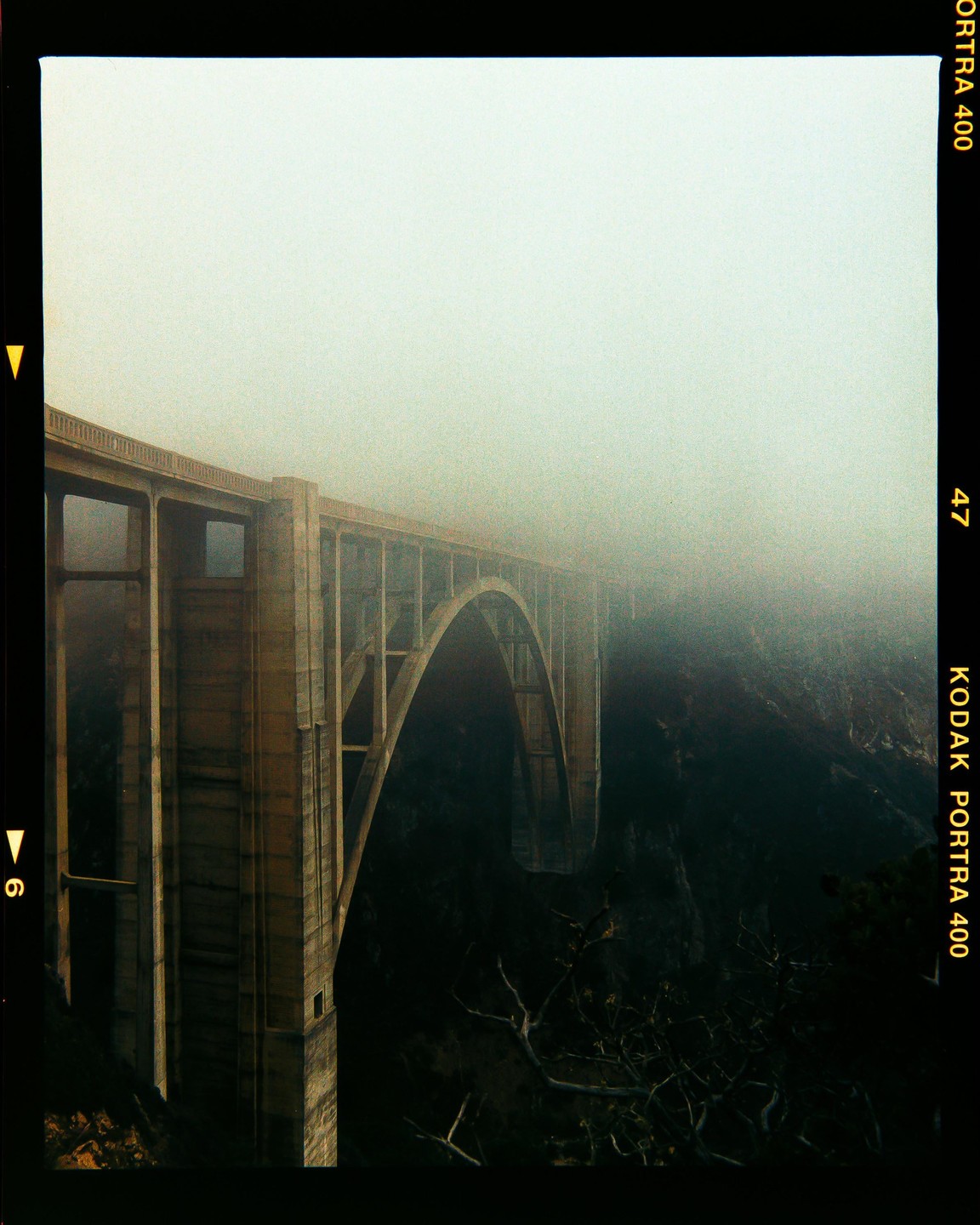 A large concrete bridge with arches extends into a thick fog.