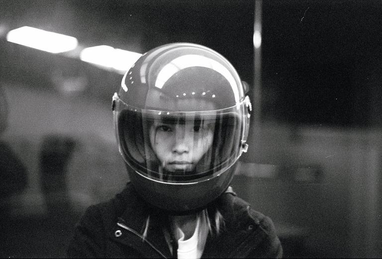 A person wearing a motorcycle helmet with a clear visor looks directly at the viewer.