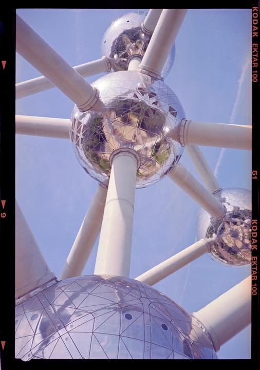 A large structure composed of interconnected spheres and tubes is set against a clear blue sky.