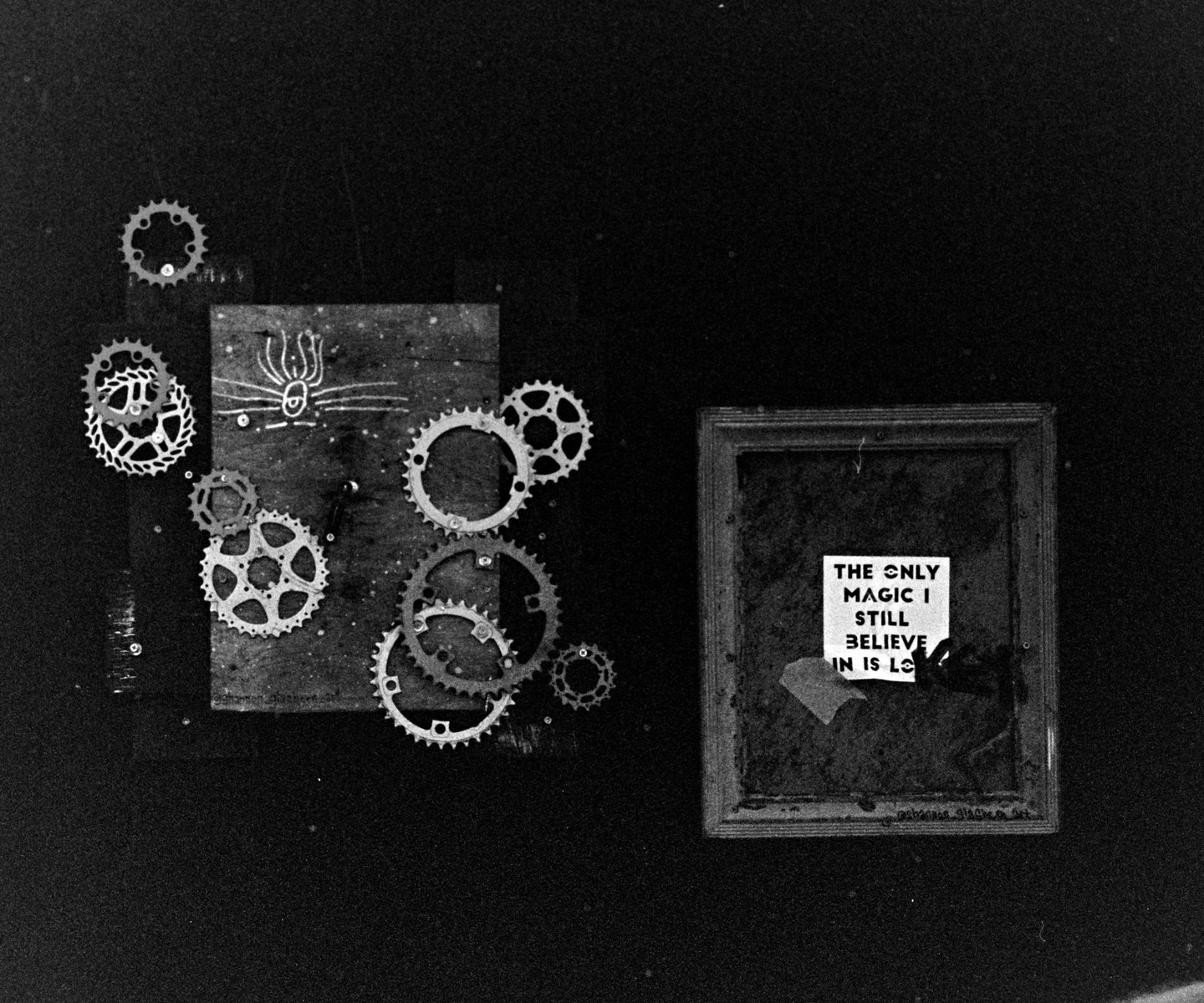 A collection of gears and a framed quote are arranged on a dark surface.