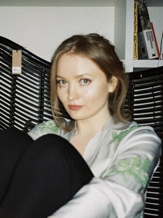 A woman with light hair and a patterned shirt is looking at the viewer.