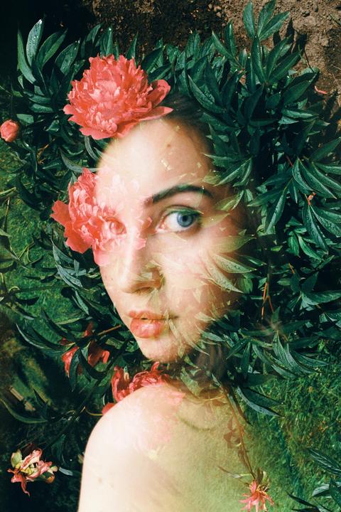 A woman's face is visible through a double exposure with green leaves and pink flowers.