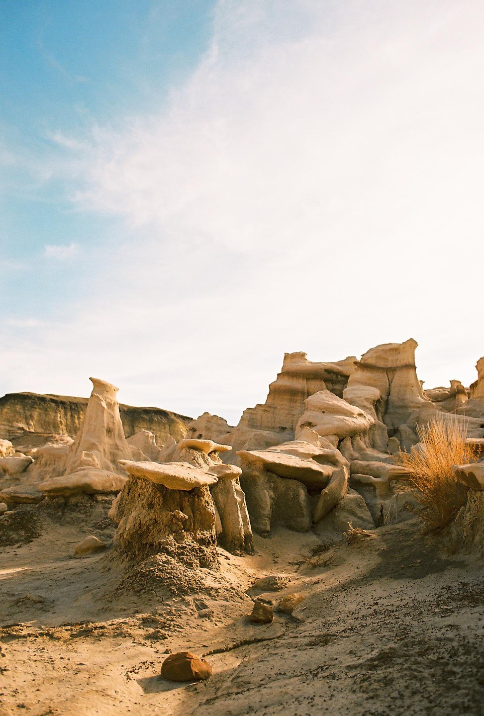 A desert landscape features rock formations under a bright sky.