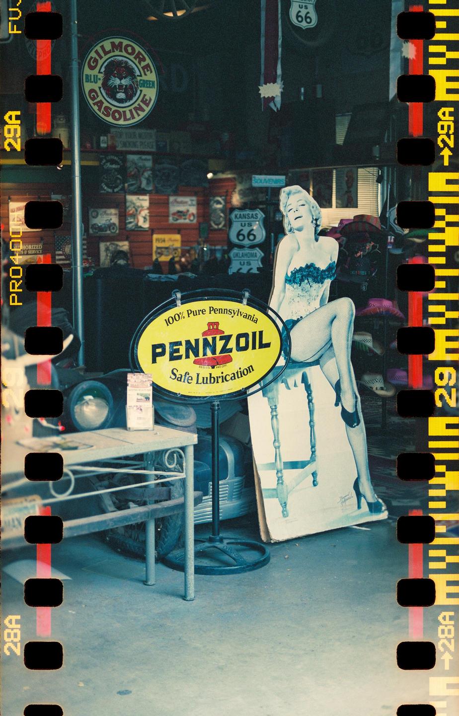 A Pennzoil sign and a Marilyn Monroe cutout stand in front of a store with Route 66 signs and other memorabilia.