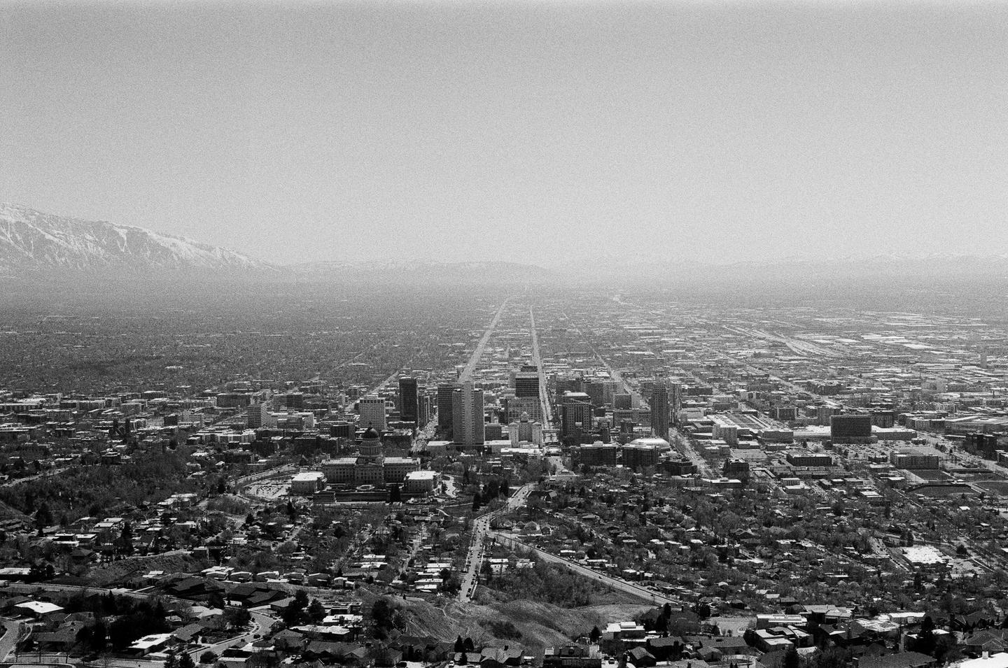 An aerial view shows a city grid stretching into the distance with mountains in the background.