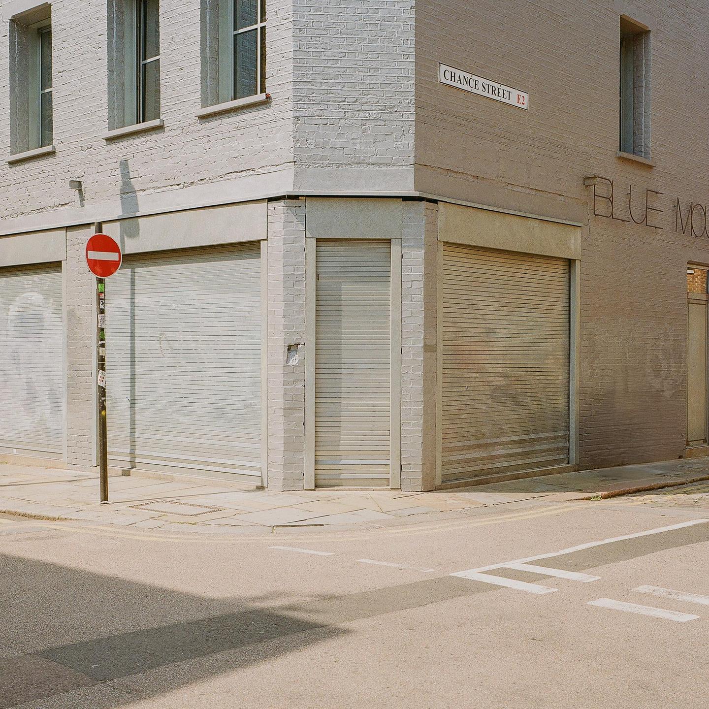 A street corner building with closed storefronts and a stop sign is visible from across the street.
