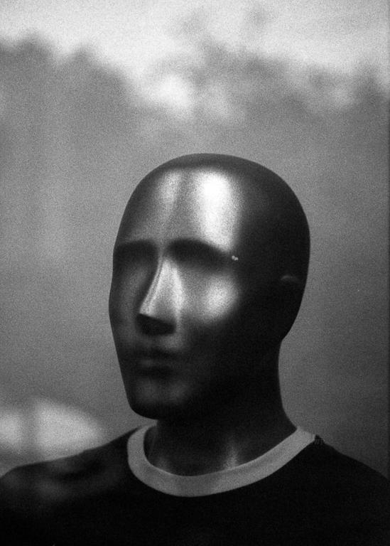 A mannequin head with a shiny surface is shown in profile, wearing a shirt with a white collar.