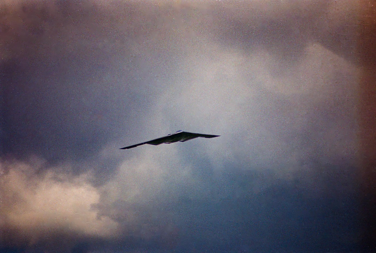 A B2 bomber flies through a cloudy sky.