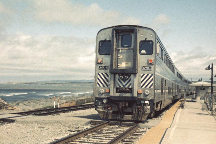 A train is parked at a station next to a beach with waves.