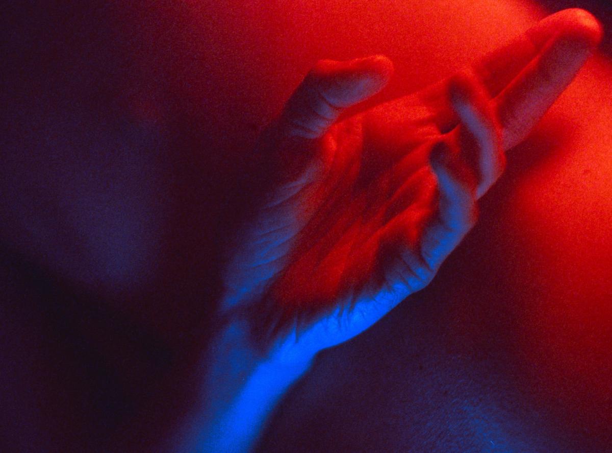 A hand is illuminated by red and blue light.