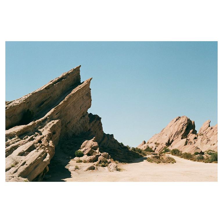 Jagged rock formations rise from a desert landscape under a clear sky.