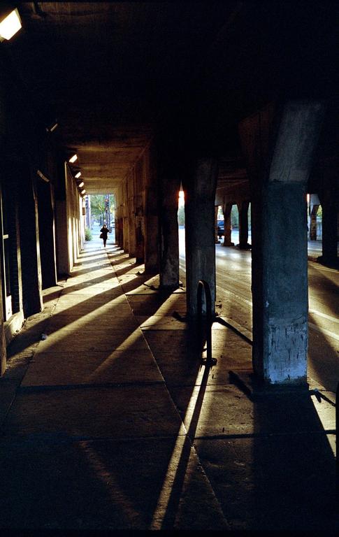 A person walks down a concrete tunnel with strong shadows cast by the setting sun.