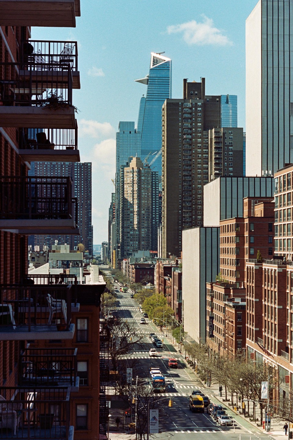 A street in New York City is visible between two tall buildings with balconies.