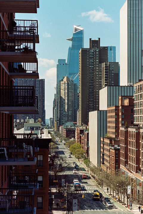A street in New York City is visible between two tall buildings with balconies.