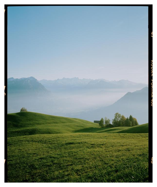 Green rolling hills are visible in the foreground, with a valley and mountains in the background.