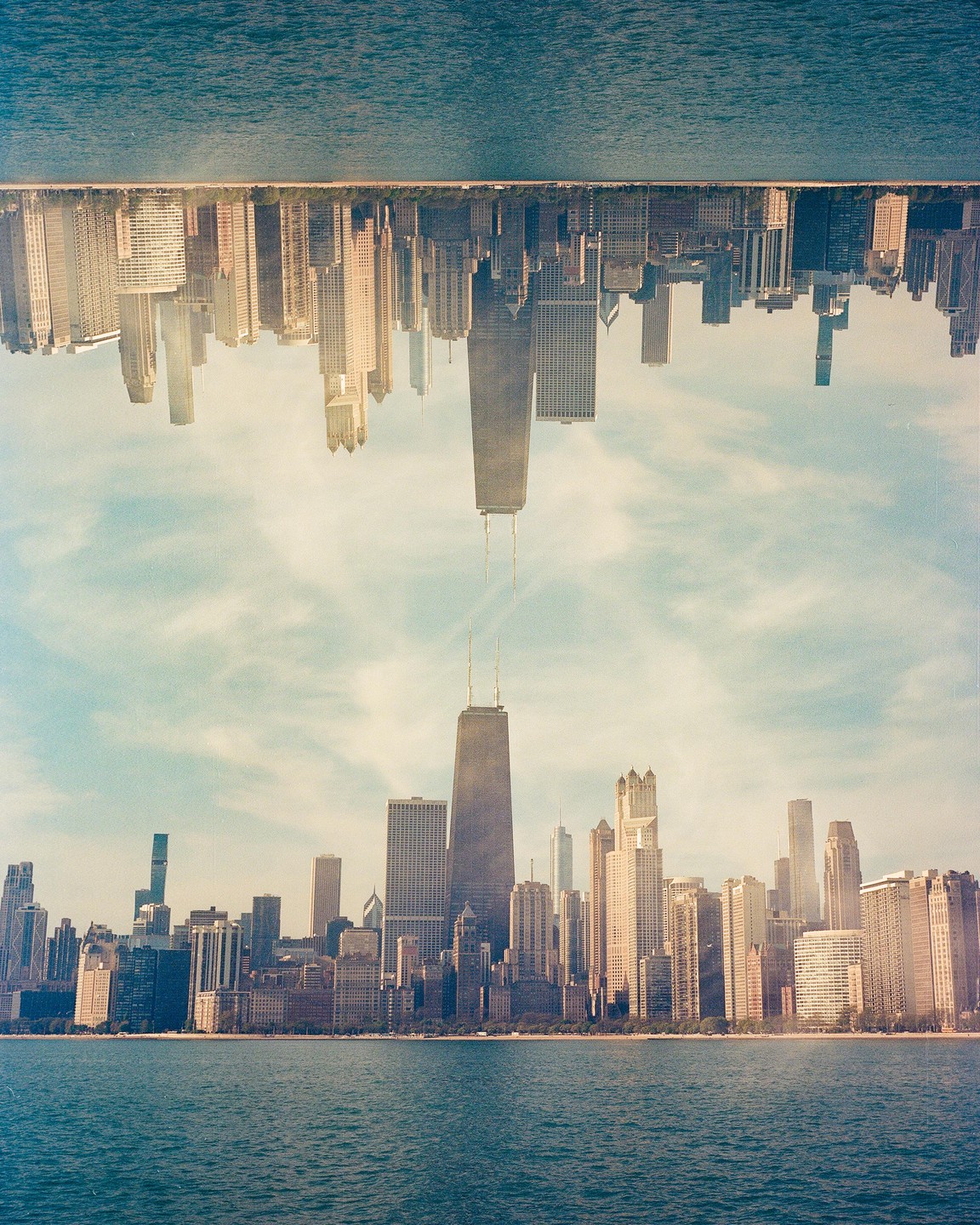 A double exposure shows the Chicago skyline right side up and upside down, with the John Hancock Center in the middle.