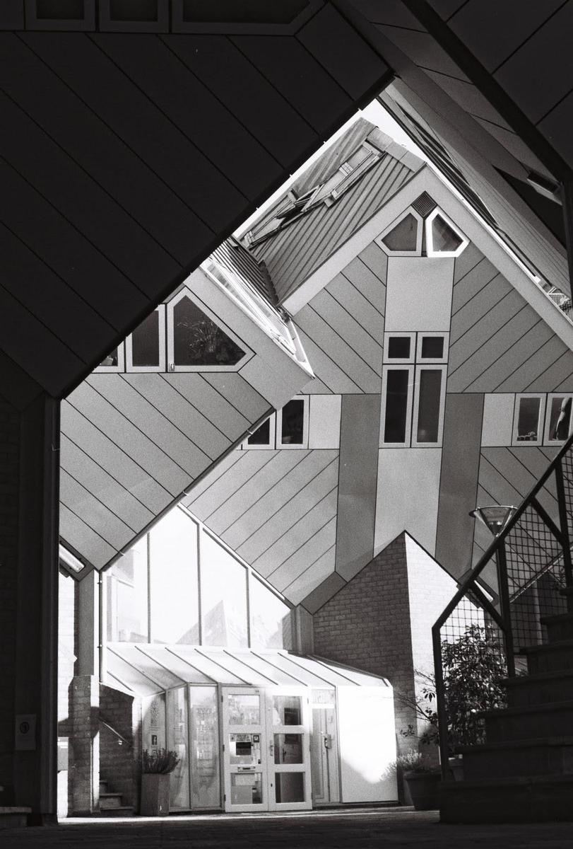 A black and white architectural photograph shows the geometric facades of the cube houses in Rotterdam.