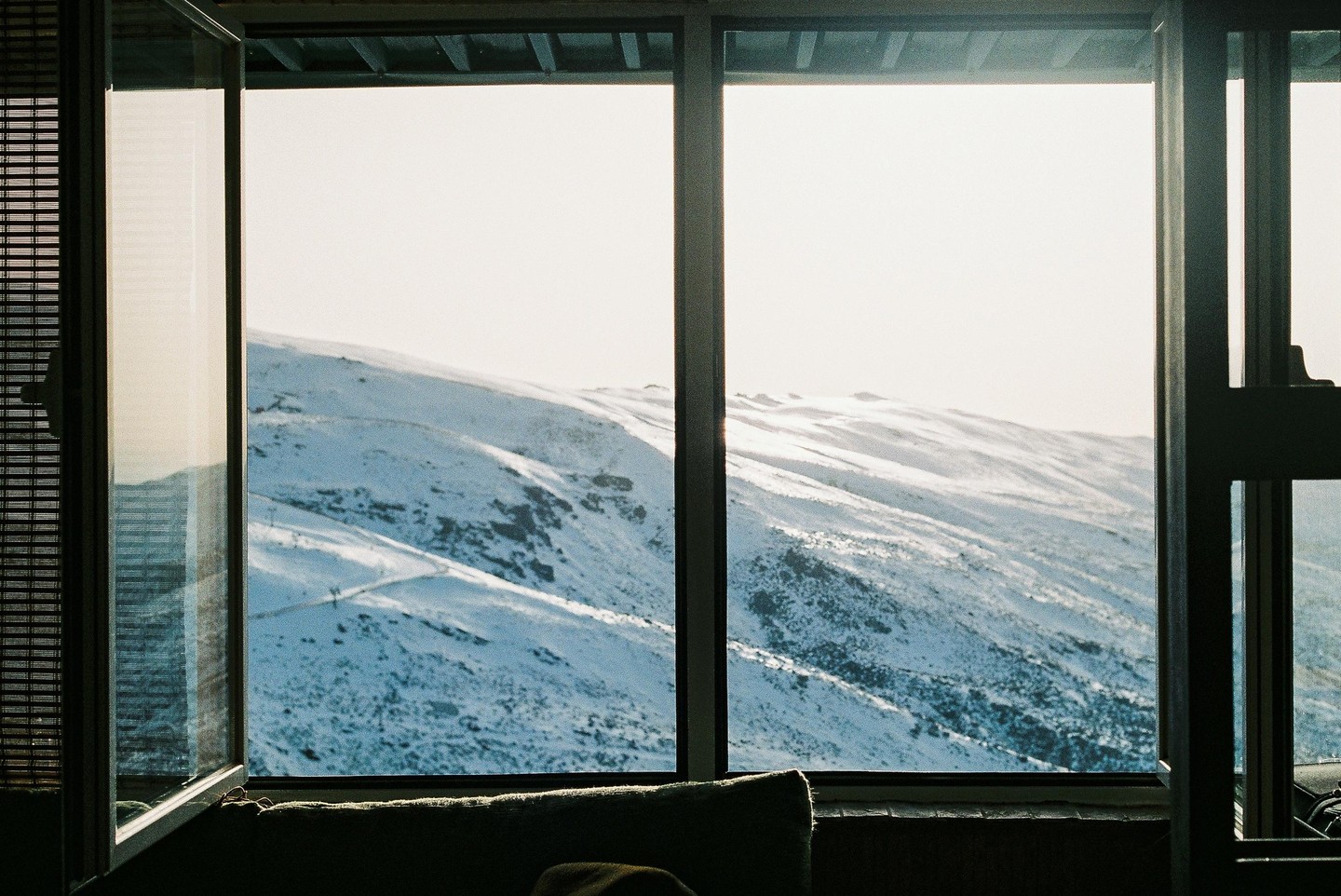 A snowy mountain landscape is visible through a large window, with one pane open.