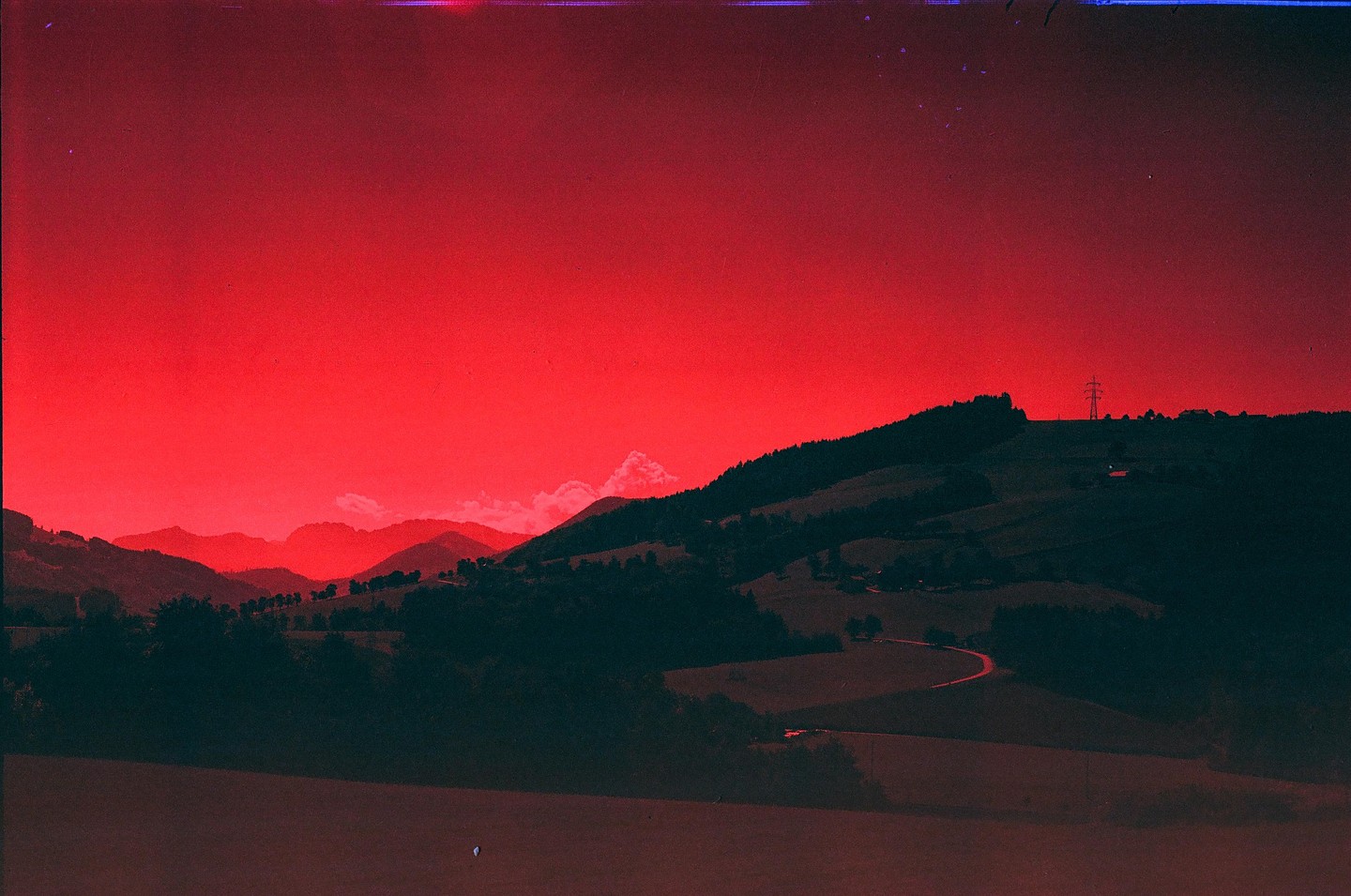 A red sky hangs over a landscape of rolling hills and mountains.
