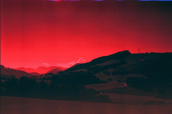 A red sky hangs over a landscape of rolling hills and mountains.