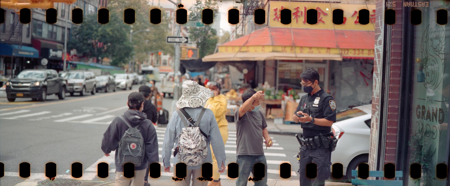 A police officer stands on a city street talking to a man while other people walk past.