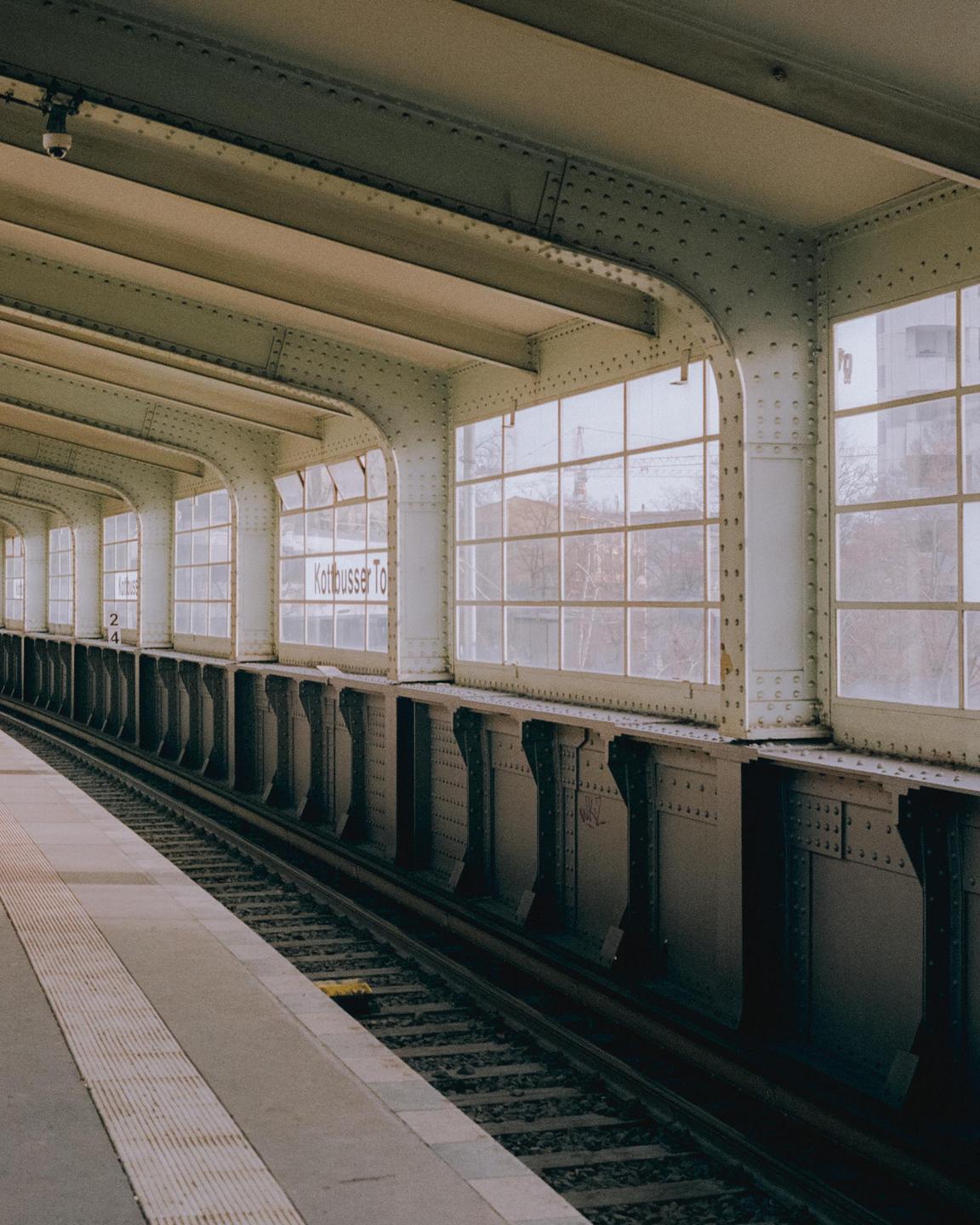 A subway platform and tracks are visible next to a wall of windows with "Kottbusser To" written on them.